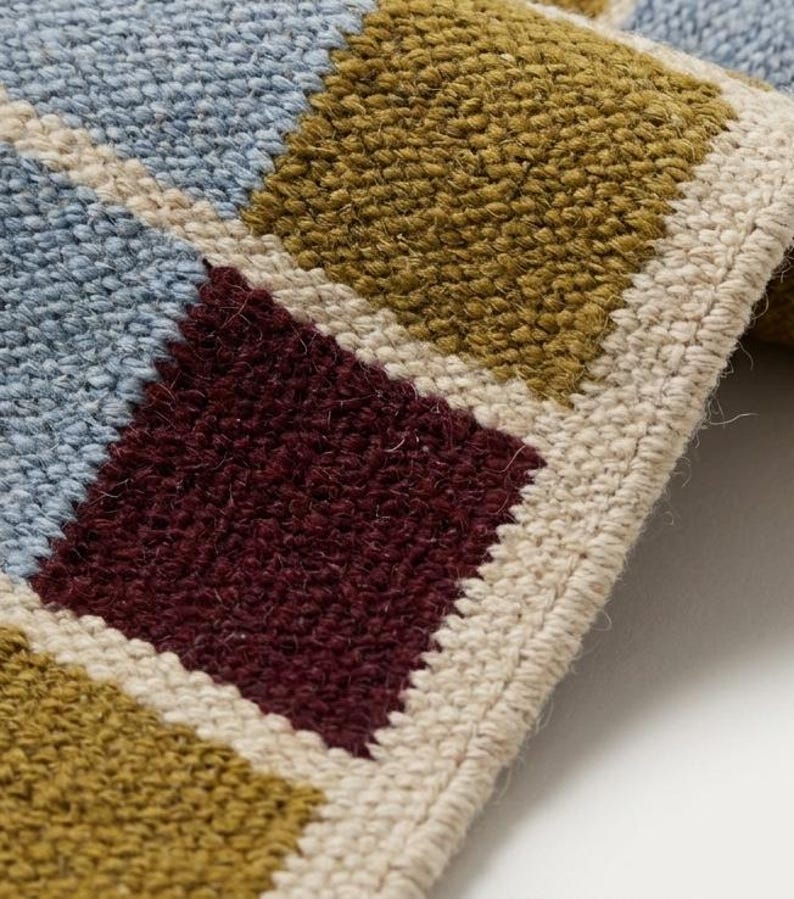 Close-up of the flatweave wool texture showing the tight reversible weave, flat no-pile surface and the interlocked yarns that form each colored square.