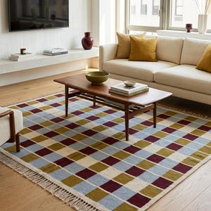 Colorful Scandinavian check area rug styled on warm oak flooring, ideal for living rooms, bedrooms and home offices with modern or boho decor.