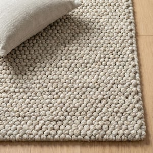 Könnte beinhalten: Nahaufnahme eines strukturierten, hellbeigen Teppichs mit einer dichten, noppigen Oberfläche. Ein hellbeiges Kissen liegt auf dem Teppich. Die Textur des Teppichs besteht aus kleinen, abgerundeten Erhebungen, die ein gemütliches, taktiles Aussehen erzeugen.