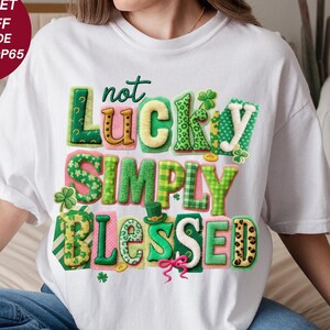 Puede incluir: Camiseta blanca con la frase "not Lucky SIMPLY Blessed" en letras coloridas, adornada con tréboles y un sombrero de duende. Las palabras "Prime Digital Shop" están impresas en la parte inferior.