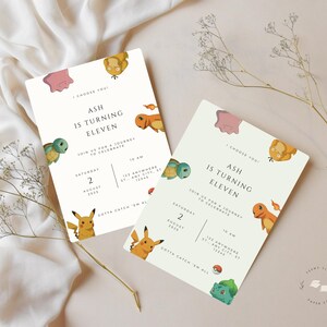 May include: Two invitation cards with a light green background and cartoon characters. The text on the cards reads "Ash is turning eleven" with event details. The cards are decorated with various Pok&eacute;mon characters and a Pok&eacute;ball.