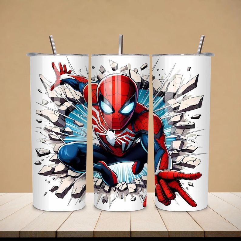 May include: Three white stainless steel tumblers with a Spiderman graphic. The design features Spiderman in a dynamic pose, breaking through a wall. The character is in a red and blue suit with a white spider emblem. Each tumbler has a silver straw.