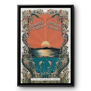 May include: A framed concert poster featuring a sunset over water with two fish swimming below. The text reads Trampled by Turtles & Leftover Salmon, Aug 7-8, 2016, Dillon Amphitheater, Dillon, CO. The border is decorated with owls, snakes, and flowers.
