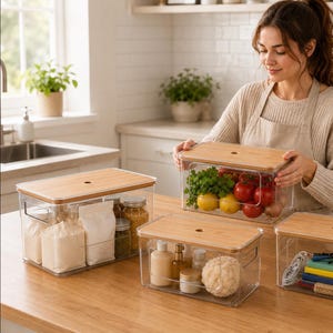 May include: A set of rectangular clear plastic storage containers with light brown bamboo lids. Each container features a small circular hole in the centre of the lid and integrated side handles. The containers hold various items like produce, dry goods, and small household objects.
