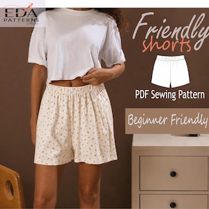 Op de afbeelding: Een persoon draagt een wit T-shirt en beige shorts met een bloemenpatroon. De shorts hebben een elastische tailleband. Tekst op de afbeelding luidt "Friendly shorts", "PDF Sewing Pattern" en "Beginner Friendly".