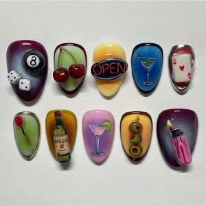 May include: A set of ten acrylic nails with various bar-themed designs. The designs include a pool ball, dice, cherries, an "OPEN" sign, a martini, playing cards, a tulip, a bottle of Jameson, a cocktail, olives, and a lighter.