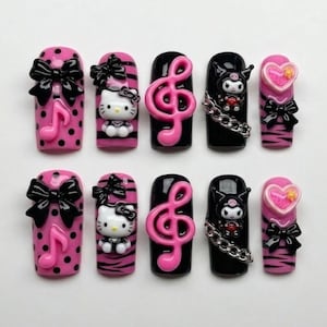 May include: A set of ten press-on nails with various designs. The nails feature a mix of pink and black colors, with embellishments like bows, musical notes, Hello Kitty, and heart-shaped charms. Some nails have a polka dot or striped pattern.