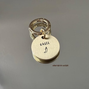 May include: A gold-coloured keyring with a round tag. The tag features the word "chilli" and a chilli pepper illustration. The keyring is attached to a gold-coloured clasp. The text "KRAFTED by KAISER" is at the bottom.