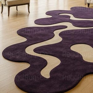 Modern Purple Abstract Wavy Rug in deep plum and beige tones, featuring curved organic shapes. Large 12x15ft contemporary area carpet perfect for living rooms or bedrooms, adding artistic style, warmth, and sophistication to any modern home interior.