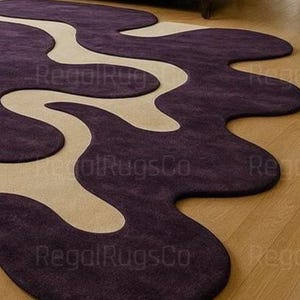 Modern Purple Abstract Wavy Rug in deep plum and beige tones, featuring curved organic shapes. Large 12x15ft contemporary area carpet perfect for living rooms or bedrooms, adding artistic style, warmth, and sophistication to any modern home interior.