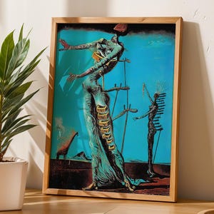 May include: A framed print of a surrealist artwork featuring a figure with outstretched arms, set against a turquoise background. The artwork has a wooden frame and is displayed on a wooden table, with a potted plant to the left.