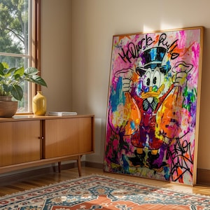May include: A framed pop art style painting featuring Scrooge McDuck holding money bags. The artwork is vibrant with pink, orange, blue, and purple paint splatters. The words "McDuck Rules" are scrawled across the top.