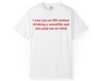 Peut inclure: Un t-shirt blanc à manches courtes avec un texte rouge imprimé sur la poitrine qui dit : I saw you on 8th avenue drinking a smoothie and you paid me no mind. Le vêtement présente une encolure ronde et une coupe standard épurée.