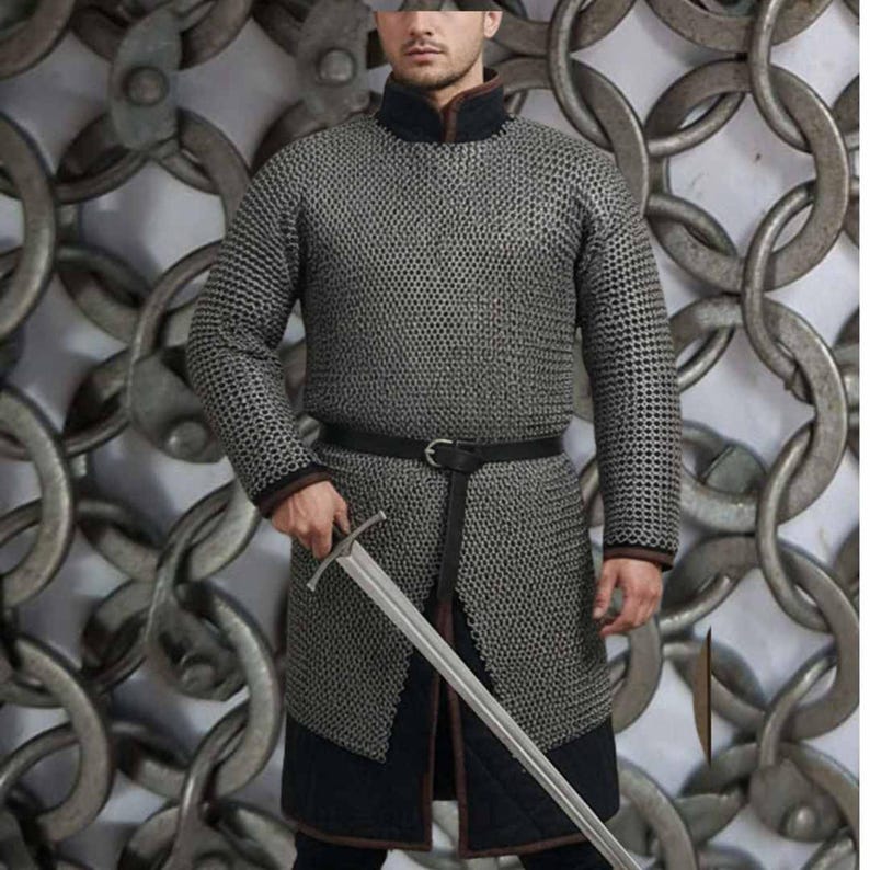 May include: A silver chainmail shirt with long sleeves, a black collar, and a black belt. The shirt extends to the mid-thigh and is paired with black pants. A silver sword is held in the right hand. The background features a chain design.