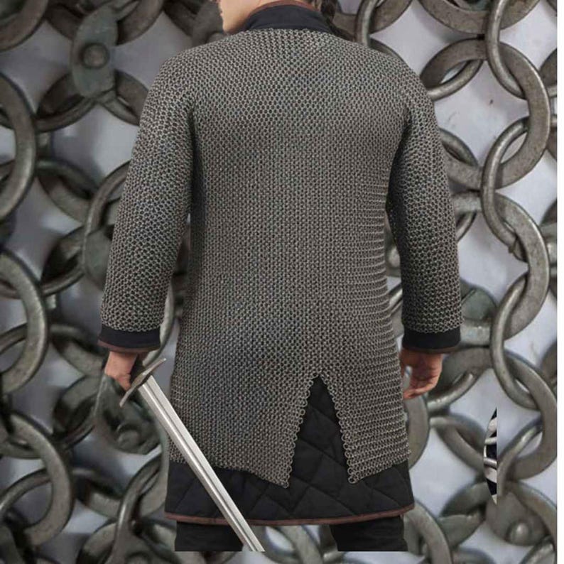 May include: A silver chainmail shirt with long sleeves and a split hem. The shirt has a black collar and cuffs. A person is holding a silver sword. The background features a large chain design.