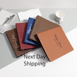 May include: A collection of personalized binders in various colors, including brown, red, and blue. Each binder features a name in elegant script, with one labeled "BOOK OF IDEAS". The image also includes a white mug and the text "Next Day Shipping".