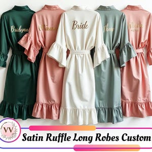 Könnte beinhalten: Fünf lange Satin-Röcke mit Rüschen in verschiedenen Farben: Smaragdgrün, Rosa, Elfenbein, Salbeigrün und Korallenrosa. Jeder Bademantel hat einen passenden Gürtel, Rüschenärmel und einen Rüschensaum. Der elfenbeinfarbene Bademantel ist mit "Bride" in Gold beschriftet.