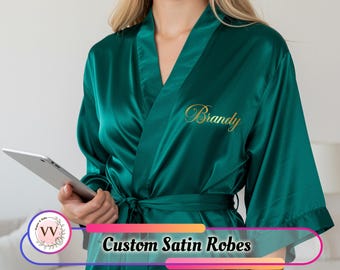 May include: Emerald green satin robe with a matching belt. The robe has gold embroidered text that reads "Brandy". The image also includes the text "Custom Satin Robes".