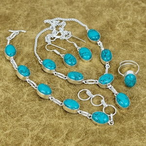 Könnte beinhalten: Ein Schmuckset mit Halskette, Armband, Ohrringen und Ring. Jedes Schmuckstück hat ovale türkisfarbene Steine in Silber gefasst. Halskette und Armband sind mit Silberketten verbunden. Die Ohrringe sind Tropfen.