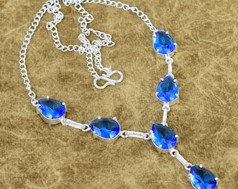 May include: A silver-toned necklace featuring five teardrop-shaped blue faceted stones arranged in a Y-shaped drop design. The necklace includes a delicate link chain with a hook clasp and an adjustable extender chain for a secure fit.