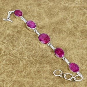 Puede incluir: Una pulsera de plata con piedras preciosas rosas ovaladas. Las piedras están engastadas en biseles individuales de plata y conectadas por eslabones de plata. Cierre de palanca.