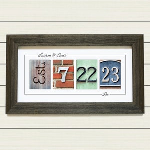 May include: A framed print with the text "Lauren & Scott - Est. 7 22 23 - Lee" in a black frame. The print features a collage of four images: a wooden sign with the word "Est.", a brick wall with the number "7", a green wall with the number "22", and a blue sign with the number "23".