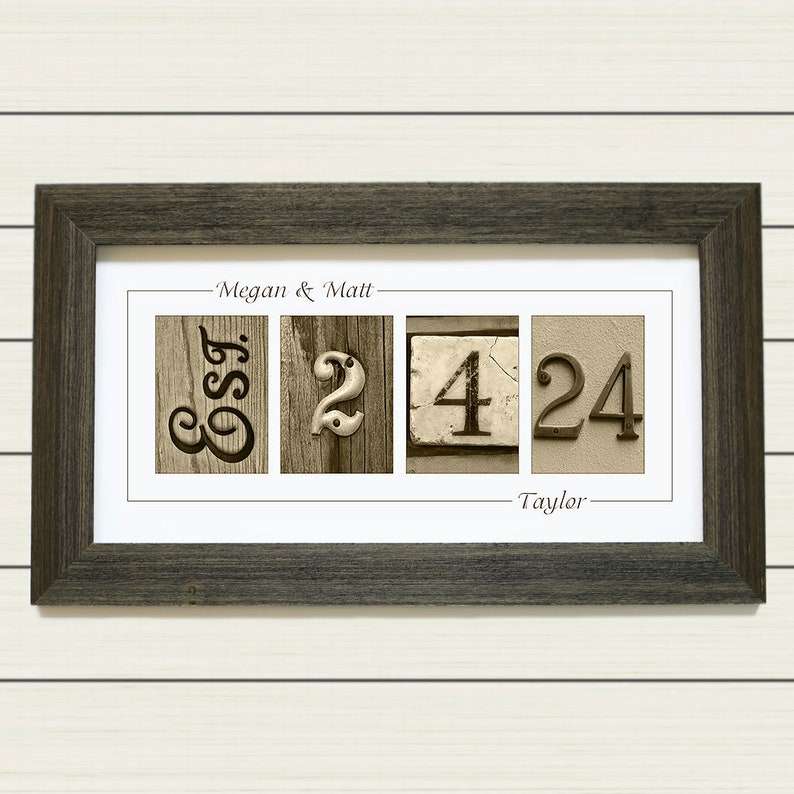 May include: A framed print with the names "Megan & Matt" and "Taylor" and the numbers "32424" in a rustic style.