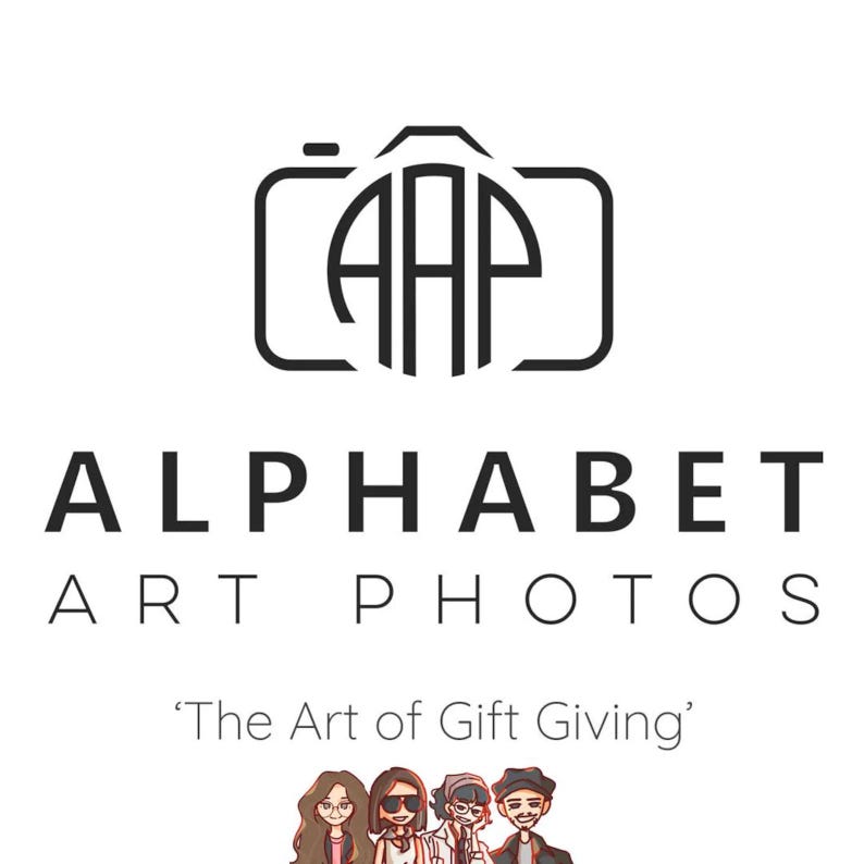 May include: Black and white logo for Alphabet Art Photos, a photography business. The logo features a stylized camera with the letters "AAP" inside a circle. The text "Alphabet Art Photos" is below the logo, and the tagline "The Art of Gift Giving" is below the text.