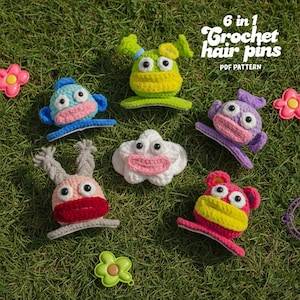 May include: Six colorful crochet hair pins in various monster-like designs, including a blue monkey, a green alien, and a pink bear. The pins are arranged on green grass with the text "6 in 1 Crochet hair pins PDF pattern".