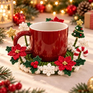 Könnte beinhalten: Ein einfarbiger roter Keramikbecher steht auf einem runden, grünen Häkeluntersetzer, der mit roten Weihnachtssternern, weißen Schneeflocken, grünen Stechpalmenblättern mit roten Beeren, einem kleinen gehäkelten Weihnachtsbaum und einer Zuckerstange verziert ist.