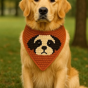Puede incluir: Un golden retriever con un pañuelo de ganchillo color óxido con un diseño de cara de perro. El perro está sentado sobre hierba verde con un fondo borroso de árboles. El pañuelo presenta detalles en negro y crema.