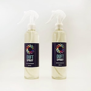 Peut inclure: Deux flacons pulvérisateurs transparents avec des buses blanches. Chaque flacon porte une étiquette noire avec les mots "DUFT SPRAY" en blanc et un motif circulaire coloré. Les flacons contiennent un liquide clair et sont étiquetés "250 ml".