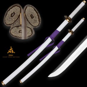 Puede incluir: Dos espadas blancas con fundas a juego, cada una con mango blanco, pomo dorado y una guarda oscura texturizada. Un cordón morado está envuelto alrededor de las fundas. Un primer plano muestra el diseño texturizado de la guarda de tres lóbulos.
