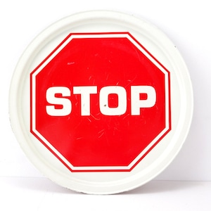 Puede incluir: Una bandeja redonda blanca con una señal de stop octogonal roja con letras blancas que dice "STOP".
