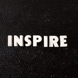 Puede incluir: La palabra "INSPIRE" escrita en letras blancas sobre un fondo negro.