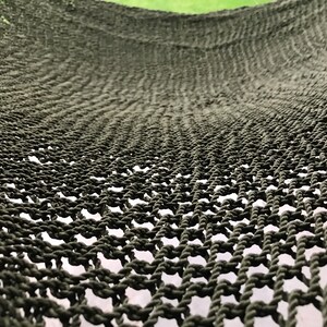 May include: Close-up of a dark green hammock made of woven rope. The hammock is hanging and the weave pattern is visible.