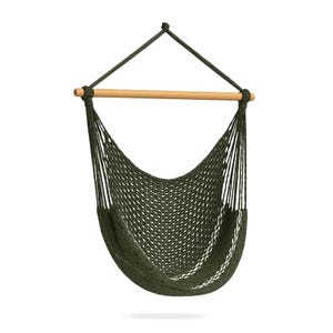 Puede incluir: Una silla colgante de color verde oliva oscuro con un diseño de red tejida, suspendida de una barra separadora de madera clara. La silla incluye cuerdas trenzadas gruesas que convergen en un solo punto superior para sujeción y soporte.