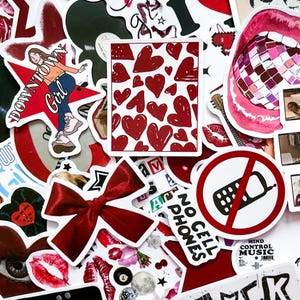 Puede incluir: Una colección de pegatinas con varios diseños, incluyendo un lazo rojo, labios, un cuadrado lleno de corazones y un gráfico de "Downtown Girl". Las pegatinas son predominantemente rojas, blancas y negras, con texto e ilustraciones.