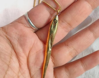 Op de afbeelding: Een gouden vishanger ketting. De hanger is langwerpig met een staartvin en een klein oogdetail. De ketting heeft een delicate gouden kleur.