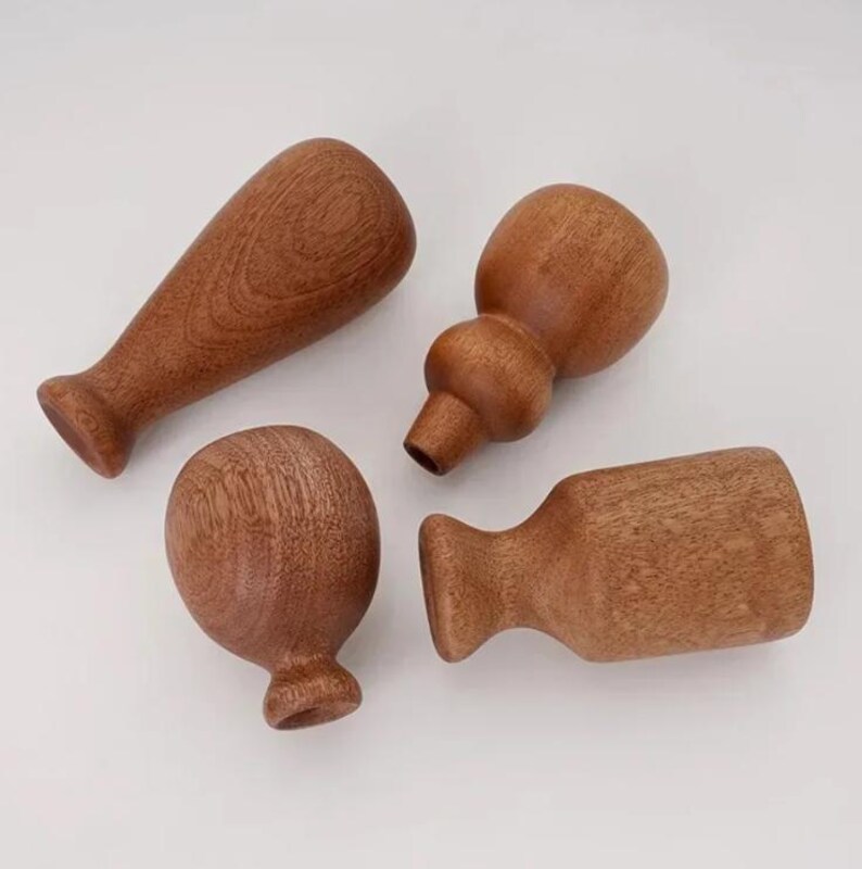 May include: Four wooden objects in various shapes, including a rounded top, a bulbous shape, and a cylindrical form. The objects are a warm brown color, with visible wood grain, and appear to be handmade. The objects are likely decorative or functional items.