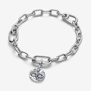 Könnte beinhalten: Ein silberfarbenes Gliederarmband mit einem runden Anhänger, der ein strukturiertes Schlangenmotiv, einen kleinen Stern und eine Mondsichel zeigt. Das Armband verfügt über einen sicheren Karabinerverschluss mit dem eingravierten Markennamen Pandora.