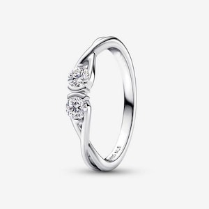 May include: A silver-toned ring featuring a twisted band design with two round, clear, faceted stones set vertically. The inner band is engraved with the text S925 ALE, indicating the metal composition and brand mark on this polished jewellery piece.