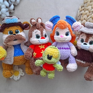 Puede incluir: Colección de cinco peluches de ganchillo hechos a mano. Los juguetes incluyen un oso con bigote, una ardilla con una camisa roja, una tortuga, un conejo con pelo naranja y una ardilla con sombrero. Cada juguete tiene detalles y colores vibrantes.