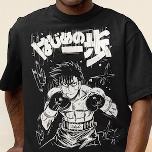 May include: Black t-shirt featuring a white graphic of a boxer in a fighting stance, wearing boxing gloves. Japanese text is above the boxer. The shirt is a crew neck style.