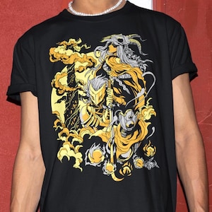May include: Black t-shirt featuring a detailed graphic design in shades of gold and yellow. The artwork depicts a fantasy scene with figures, including a warrior and a woman with horns, set against a backdrop of stylized clouds.