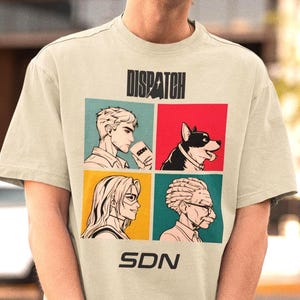 Puede incluir: Camiseta beige claro con un diseño gráfico. El diseño presenta la palabra "DISPATCH" encima de cuatro paneles, cada uno con una ilustración diferente. Las letras "SDN" están impresas debajo.