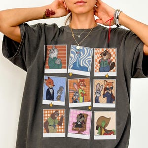May include: Dark grey Comfort Colors tee featuring nine cartoon character polaroid-style images. The images are of various anthropomorphic animals. The shirt has the text "Comfort Colors Tee (PEPPER)" at the bottom.