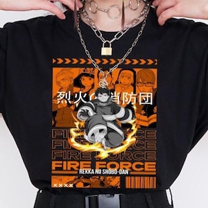 May include: Black t-shirt with a graphic design from the anime Fire Force. The design includes Japanese text, character illustrations, and the words "FIRE FORCE" in orange and white. The shirt has a crew neck and short sleeves.