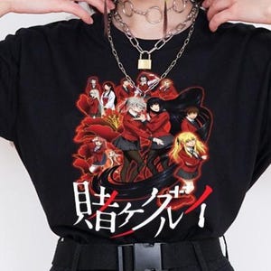 May include: Black t-shirt featuring a graphic design with multiple characters in red and white. The Japanese text is printed in white. The shirt is paired with black pants and a black belt.