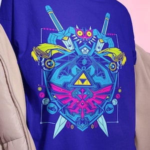 May include: A royal blue t-shirt with a colourful geometric design. The graphic includes a shield, swords, and a triangle, with yellow, pink, and blue accents. The design is centred on the shirt.